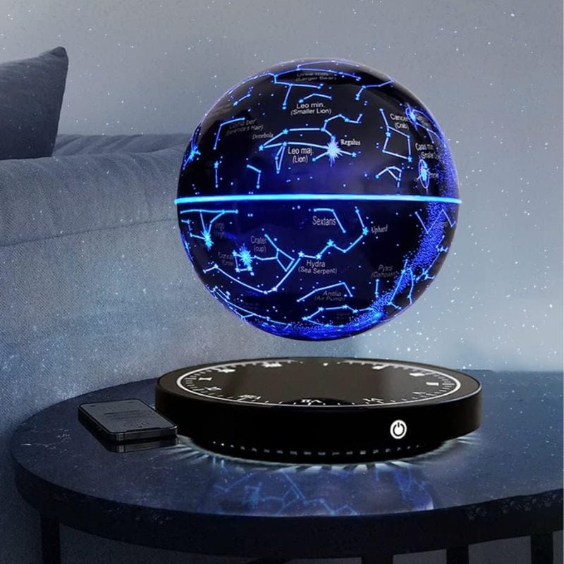 Globe céleste lumineux avec constellations et étoiles, projeté sur une surface noire, illuminant la pièce avec un effet stellaire.