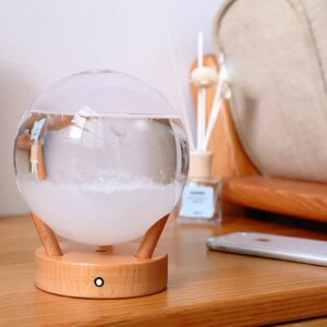 Un diffuseur d'huiles essentielles en forme de globe, placé sur une table en bois, avec un décor de bureau ou de salon moderne.