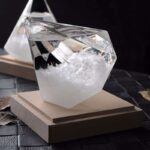 Cube en verre transparent contenant un liquide clair, posé sur une base en bois, idéal pour la décoration de style scientifique ou contemporain.