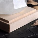 Pièce de bois brut utilisée comme support pour une expérience scientifique ou une décoration, avec un marteau en arrière-plan, sur une surface noire.