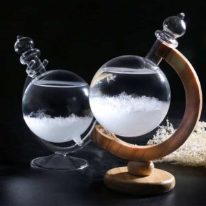 Vase en verre contenant un liquide transparent avec des cristaux ou des particules, posé sur une base en bois courbée, avec un fond noir pour mettre en valeur l'objet.