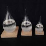Pipettes en verre contenant un liquide transparent, disposées sur des supports en bois de différentes tailles, illustrant un phénomène scientifique ou une expérience de laboratoire.