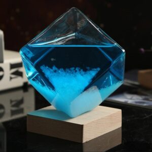 Panneau de verre en forme de cube contenant un liquide bleu avec une poudre blanche au fond, posé sur un socle en bois, illustrant un objet scientifique décoratif.