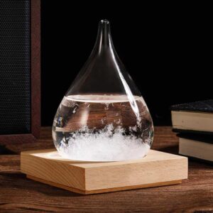 Pendentif en verre en forme de goutte d'eau contenant un liquide transparent, posé sur une base en bois, idéal pour la décoration scientifique ou comme accessoire original.