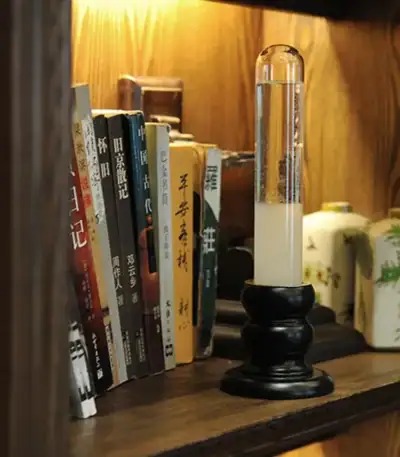 Lampe de laboratoire vintage avec liquide dans un tube à essai, placée sur une étagère en bois avec des livres anciens et des objets décoratifs.