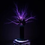 Illustration d'une décharge électrique statique violette émanant d'une sphère, exposée dans un environnement sombre, représentant une expérience scientifique ou un phénomène électrique.