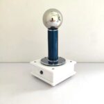 Dispositif de démonstration scientifique avec sphère en acier inoxydable, base en bois et support en métal, utilisé pour illustrer les principes de la physique électrique.
