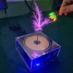 Platine de DJ miniature avec plume lumineuse et LEDs colorées, idéale pour décoration scientifique ou événement musical.