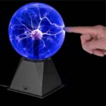 Boule de plasma interactive avec doigt, affichant des éclairs lumineux, sur un socle noir, illustrant la science et la technologie.