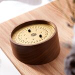Horloge scientifique en bois avec cadran doré et deux aiguilles noires, posée sur une table en bois clair, décoration élégante et moderne.