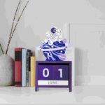 Panneau calendrier en bois violet avec un robot et un univers cosmique en décoration intérieure.