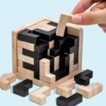 Puzzle en bois avec pièces noires et naturelles, en cours d'assemblage dans une boîte en bois, illustrant un jeu de réflexion et de décoration scientifique.