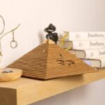 Pyramide en bois avec horloge intégrée, décoration de style scientifique et vintage, posée sur une étagÚre en bois clair.