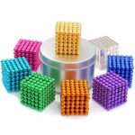 Ensemble de cubes magnétiques colorés en acier, utilisés comme jouets de construction ou décoration, avec un cube doré placé sur un support métallique.