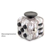 Cube décomprimé avec boutons noirs et surface camouflage, utilisé comme objet de décoration ou pour la détente mentale.
