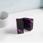 Cube puzzle noir avec éclaboussures roses, pièce de décoration scientifique moderne, idéal pour les amateurs de design innovant et d'objets décoratifs originaux.