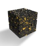 Éclaboussures dorées sur un cube puzzle noir, décoration moderne et originale.