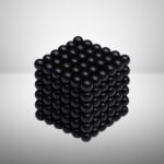 Billes noires formant un cube tridimensionnel, utilisé comme objet décoratif ou expérimental en science.