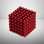Billes métalliques rouges formant un cube tridimensionnel, brillant et réfléchissant, utilisé comme objet de décoration scientifique ou de bureau.