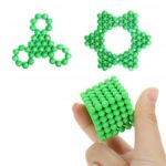 Paire de modèles moléculaires en 3D en forme de triskel et d'étoile, avec une main tenant un cube en sphères vertes. Idéal pour l'apprentissage scientifique et la décoration éducative.