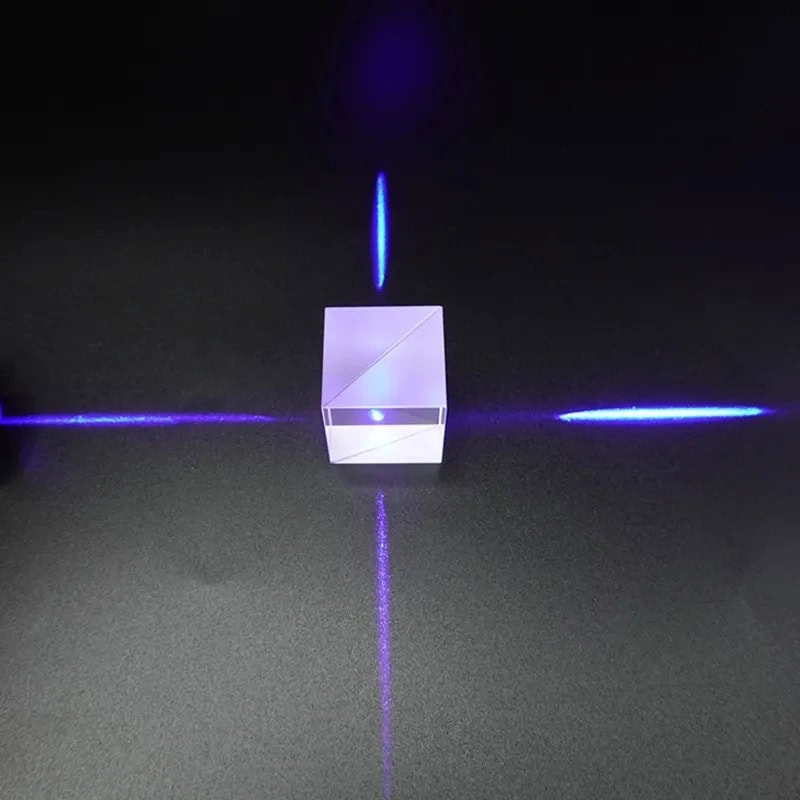 Porte-laser en verre transparent avec lumière bleue, projetant des lignes lumineuses sur une surface noire, créant un effet visuel futuriste et scientifique.