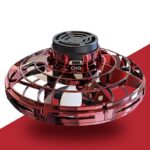 Véhicule spatial miniature en plastique rouge transparent avec détails noirs, représentant un engin de science-fiction ou un drone futuriste, posé sur un fond rouge.