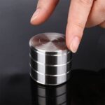 Piles de disques métalliques empilés, utilisés dans des expériences scientifiques ou des démonstrations de physique, avec une main manipulant la pile.