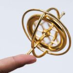 Pendentif en forme d'atome en métal doré, illustrant un modèle scientifique, parfait pour la décoration ou comme bijou inspiré de la science.
