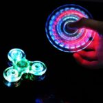 Poupée à main avec fidget spinner LED coloré en rotation.