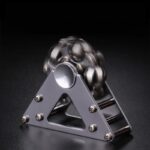 Pyramide de balles métalliques en équilibre sur une base en métal, illustrant un phénomène physique ou une expérience scientifique.
