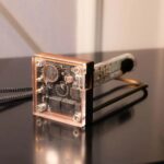 Puce électronique scientifique avec boîtier en bois, composants électroniques visibles, utilisée pour des expériences ou démonstrations scientifiques.