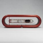 Porte-ballon de baudruche en verre avec cadre en bois rouge, idéal pour la décoration scientifique ou festive, combinant élégance et originalité.