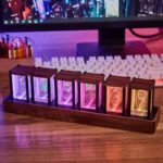 Nixie tubes lumineux dans une boîte en bois, affichant des chiffres colorés, parfaits pour la décoration scientifique ou vintage.