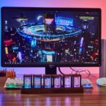 Écran d'ordinateur affichant une ville futuriste illuminée avec des objets scientifiques lumineux en premier plan, parfait pour la décoration de bureau ou d'espace scientifique.