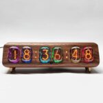 Horloge vintage avec tubes lumineux colorés affichant l'heure 18:36, montée sur un support en bois, style rétro et décoratif pour un intérieur original.