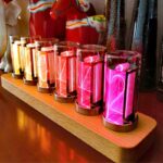 Nombres de Nixie lumineux en couleurs variées sur un support en bois, parfaits pour la décoration scientifique ou vintage.