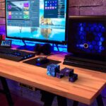 Réseau informatique et accessoires de bureau modernes sur un bureau en bois, incluant un ordinateur, un clavier, une souris, un casque audio, et des cubes de décoration scientifique luminescents.