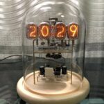 Horloge à Nixie affichant l'année 2029, avec tubes lumineux dans une cloche en verre.