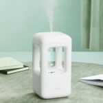 Diffuseur d'huiles essentielles blanc en forme de cube, diffusant de la vapeur aromatique dans une pièce.