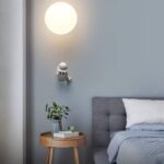 Lampe de nuit robotique en forme de petit robot blanc projetant une lumière douce, idéale pour une décoration de chambre moderne et ludique.