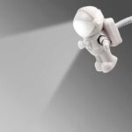Mini astronaute en plastique blanc projetant une lumière, idéal pour décoration de bureau ou espace scientifique.