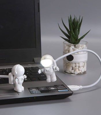 Mini astronautes en plastique suspendus au câble de l'ordinateur portable, créant une scène ludique et scientifique.