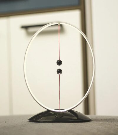 Péndule de Newton en décoration scientifique, illustrant la physique avec deux sphères suspendues dans un cadre circulaire, parfait pour une décoration de bureau ou d'espace éducatif.