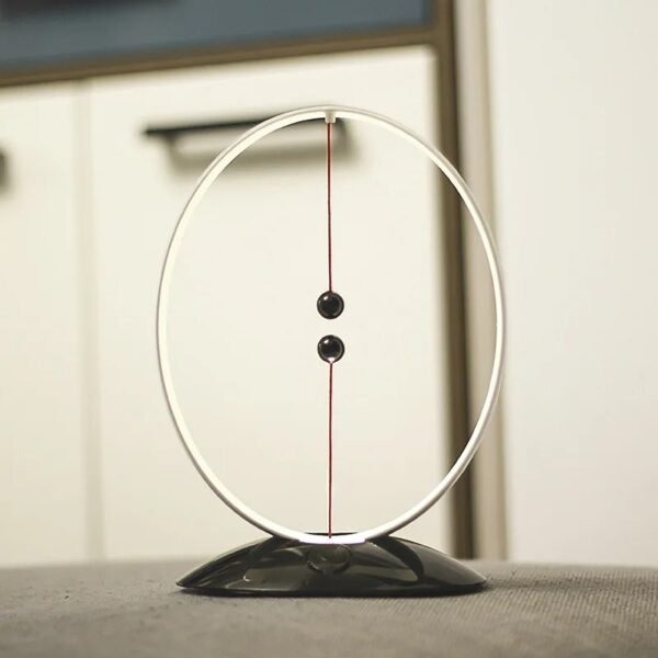 Péndule de Newton en décoration scientifique, illustrant la physique avec deux sphères suspendues dans un cadre circulaire, parfait pour une décoration de bureau ou d'espace éducatif.