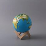 Terre miniature avec continents en relief, sur support en bois, utilisé comme objet décoratif ou éducatif.