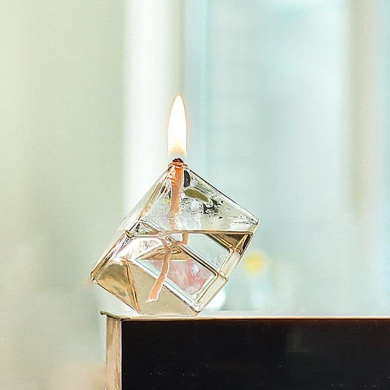 Porte-encens en forme de cube en verre avec flamme allumée, idéal pour la décoration scientifique et moderne.