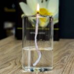 Bougie allumée avec mèche visible dans un verre d'eau, créant un effet visuel intéressant. Parfait pour une décoration scientifique ou un objet de collection.