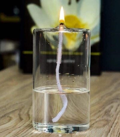 Bougie allumée avec mèche visible dans un verre d'eau, créant un effet visuel intéressant. Parfait pour une décoration scientifique ou un objet de collection.