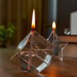 Pyramide en verre avec bougies allumées, décoration scientifique et moderne, idéale pour une ambiance chaleureuse et élégante.