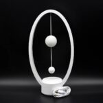 Horloge scientifique moderne avec deux sphères suspendues dans un cadre ovale blanc, idéale pour la décoration de bureau ou d'espace éducatif.